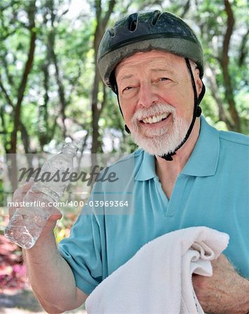 A senior man taking a break from exercise to towel off and have a drink of water.