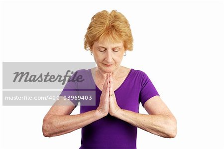 A senior woman in her seventies beginning her yoga routine by deep breathing.  Isolated on white.