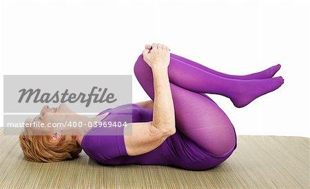 Fit seventy year old woman enjoys doing yoga.  White background.