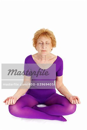 A fit seventy year old woman meditating during a yoga practice.  White background.