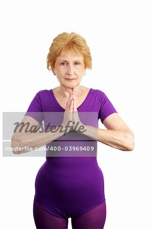 A seventy year old seniori lady becoming calm in preparation for doing yoga.  Isolated on white.