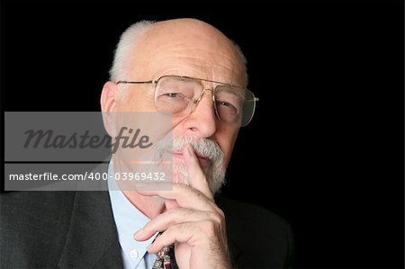 An intelligent senior man with a thoughtful expression over a black background.