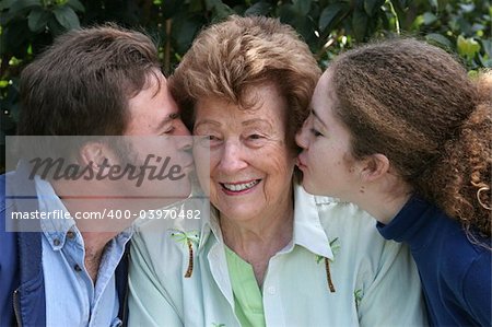 A sweet grandmother receiving kisses from her family.