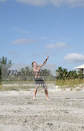 A young man parasailing on the beach.