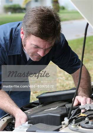 An auto mechanic looking under the hood of a car. Vertical view.