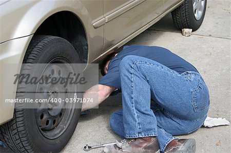 A mechanic reaching under a car.