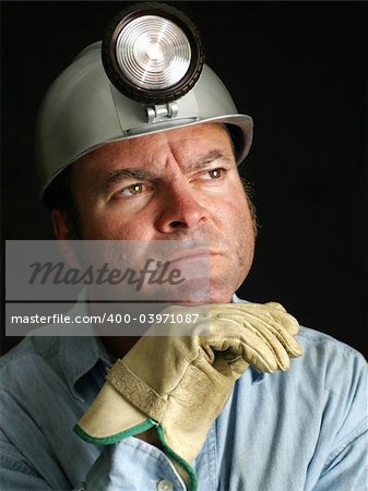 A black and white portrait of a coal miner with a thoughtful expression.