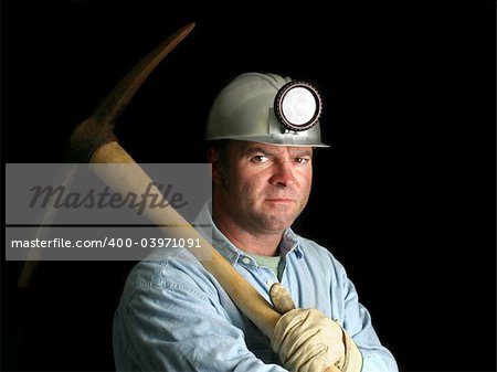 A coal miner with his pickax, in the darkness of a mine shaft.