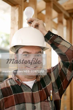 A construction worker in a hardhat holding a lightbulb over his head.