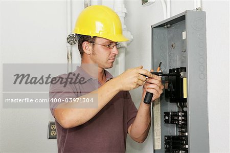 An electrician working on an industrial breaker panel.  Model is an actual electrician performing all work to industry codes and safety standards.