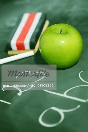 Green apple on chalkboard with easer/ Green