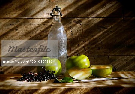 Old bottle and green apples with wood background