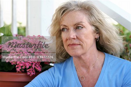 A beautiful mature woman sitting on her front porch thinking with a faraway look in her eyes.