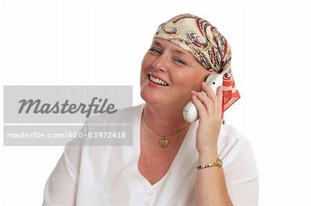 A woman, bald from medical treatment, receiving good news by telephone.