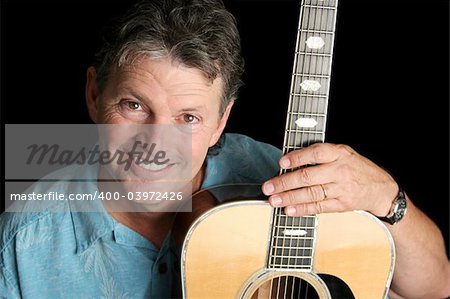 A handsome middle aged musician smiling with his guitar.