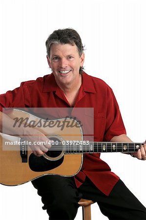 A handsome mature musician smiling as he strums his guitar.  Isolated.