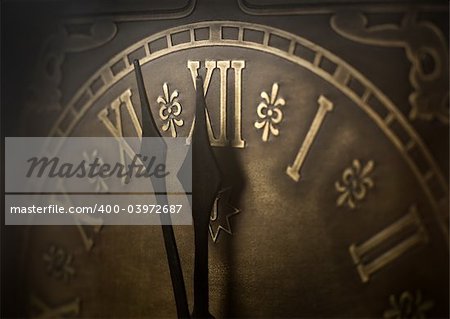 Old clock with roman numerals. Selective focus on  number XII and minute hand. Intentional vignetting.