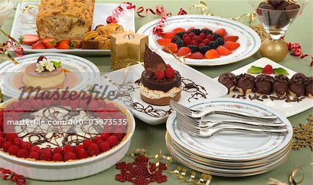 Elegant table with many desserts and fruits (eclair, pecan swirl cake, raspberry pie, rice pudding, cheese cake, creme caramel, and more)