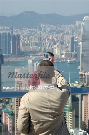 Young man taking photo for his friend by mobile phone