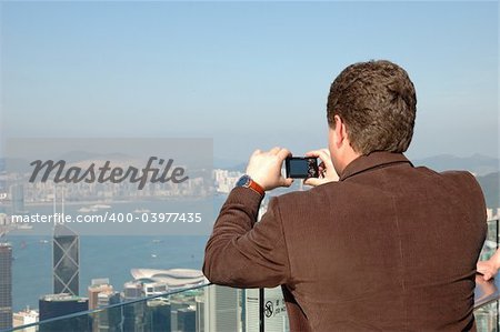 Tourist taking photo of Hong Kong skyline by his digital camera