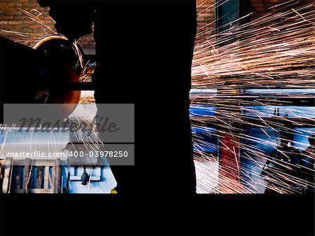 Metal cutting with worker silhouette and fire sparks