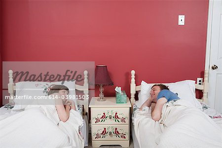 Young couple smiling at each other in single beds