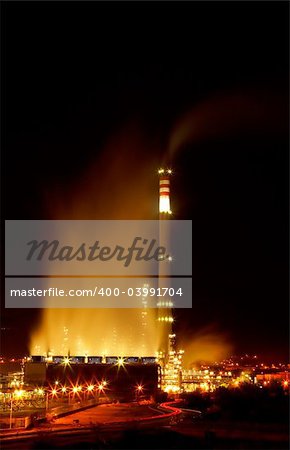 Night view of a petrochemical refinery with chimneys and storage tanks