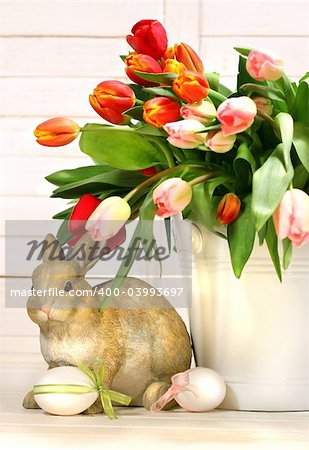 Little rabbit behind white container full of tulips