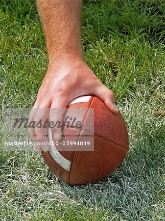 a football players hand on the ball