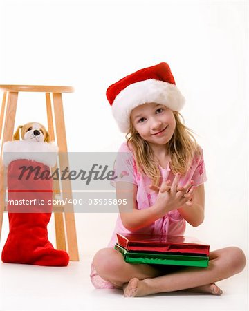 cute little eight year old girl sitting on floor with christmas presents holding a little stuffed dog