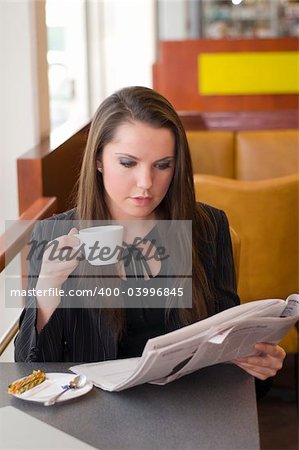 business woman relaxing in a bar drinking coffee and reading news paper