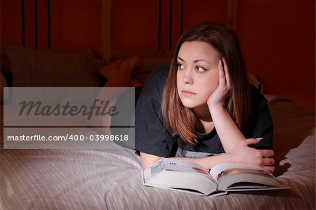 A girl with a book in the bedroom.