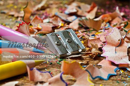 colored pencils sharpener and shavings on wooden surface