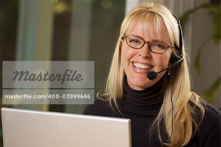 Attractive businesswoman smiles as she talks on her phone headset.