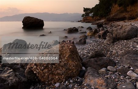 Image shows a rocky mediterranean seascape, photographed with a long exposure right after sunset.