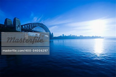 View of Sydney Harbour with Sydney Harbour bridge and distant skyline at dusk in Sydney, Australia.