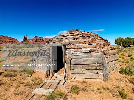 Desert landscape with rustic log cabin shelter.