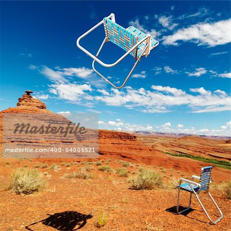 Lawn chair thrown in midair in scenic desert landscape with land formation.