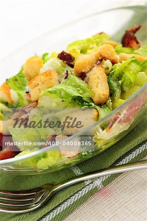 Caesar salad with croutons and bacon bits served in a glass bowl
