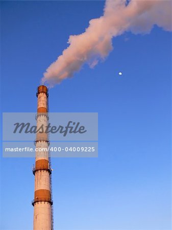 Factory pipe smoking with a white smoke and a moon nearby over the blue sky
