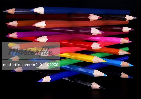 Top view of colorful pencils tower isolated over black background