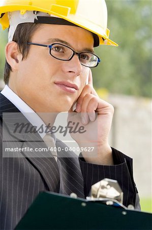 A young male manager in hard hat making a phone call