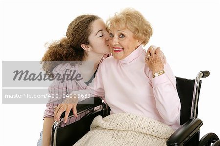 Senior woman smiles as she gets a kiss from her granddaughter.  Isolated on white.