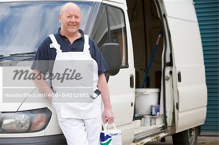 Decorator Standing Next To White Van With Paint in Hand