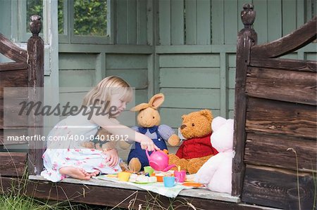 Young girl having doll's tea party in a summerhouse