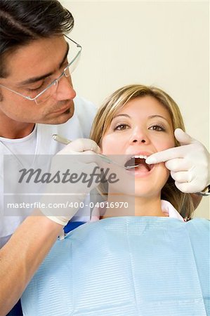young woman doing dental checkup. Dentist is using an angled mirror