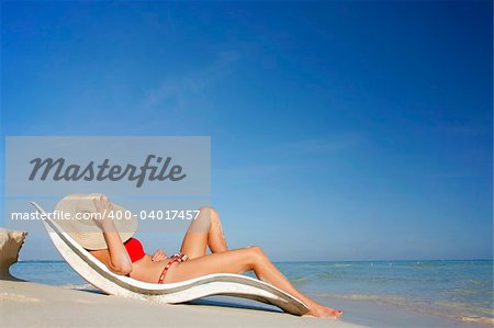 One of a long series of photos taken on the Mexican Caribbean coast. Woman sunbathing on luxury white recliner.