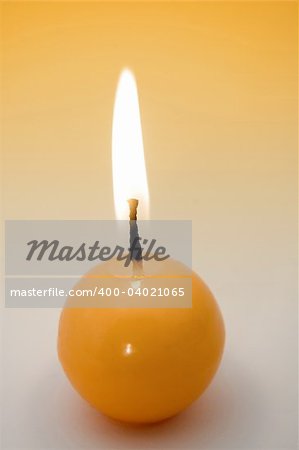 small yellow burning candle, yellow to grey background
