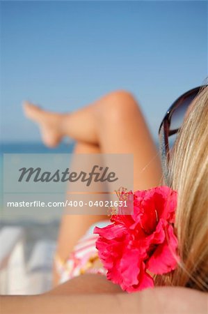 Woman sunbathing on a sun lounger on a tropical beach