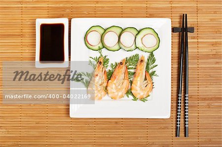 Plate of prawns with soy sauce on bamboo mat. Shallow depth of field